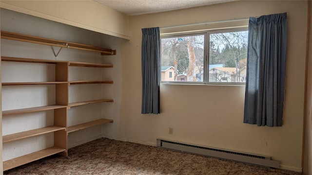 carpeted empty room with a baseboard heating unit and a textured ceiling