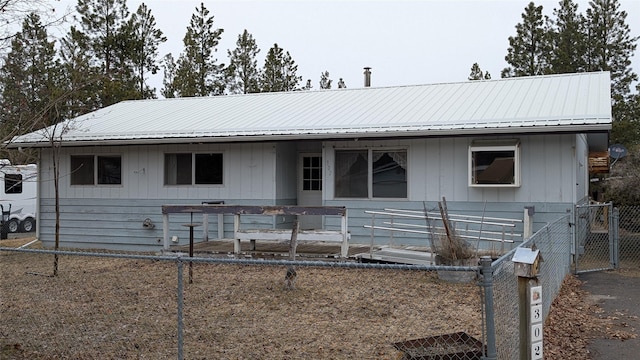 ranch-style house with metal roof and fence