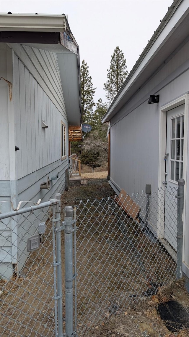 view of side of home with a gate, fence, and crawl space