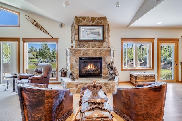 living room featuring a stone fireplace, vaulted ceiling, and wood finished floors