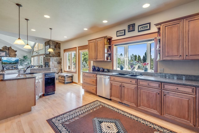 kitchen featuring hanging light fixtures, dishwasher, light wood-type flooring, and a sink