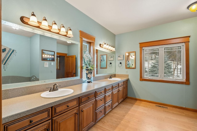 full bathroom with baseboards, wood finished floors, visible vents, and a sink