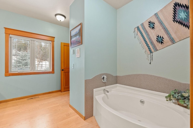 full bath with a bath, wood finished floors, visible vents, and baseboards