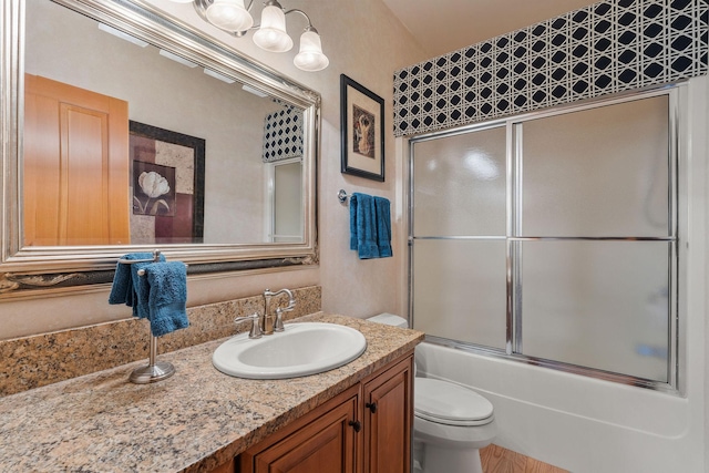 full bath with toilet, vanity, and bath / shower combo with glass door