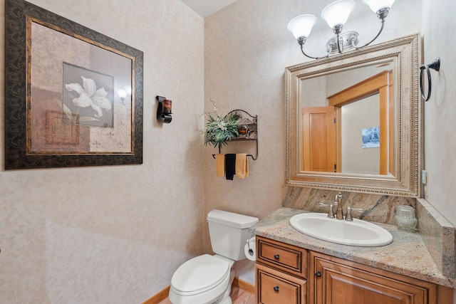 bathroom featuring vanity, a notable chandelier, toilet, and baseboards