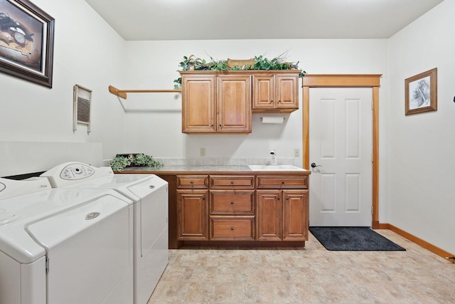 clothes washing area featuring a sink, cabinet space, baseboards, and washer and clothes dryer