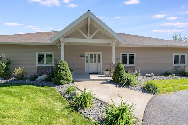 view of front of house featuring stone siding, a porch, and a front lawn