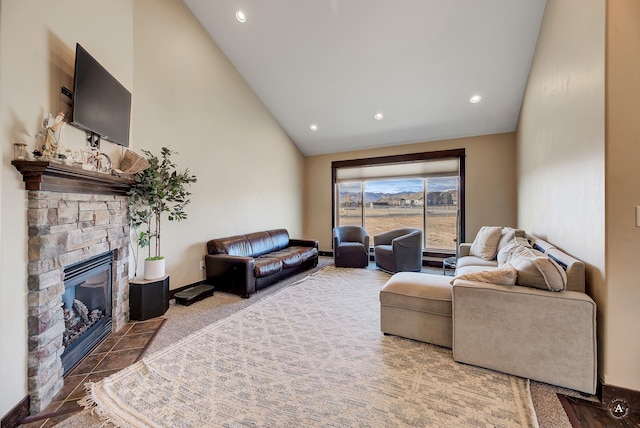living room with recessed lighting, baseboards, high vaulted ceiling, and a stone fireplace