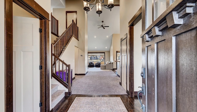 entryway featuring baseboards, dark wood finished floors, stairs, a towering ceiling, and a notable chandelier