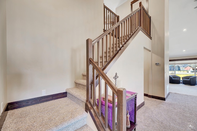stairs featuring a towering ceiling, recessed lighting, baseboards, and carpet floors