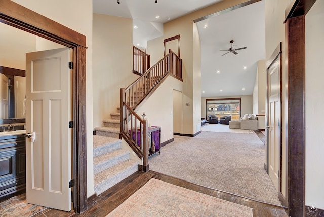 stairway with a ceiling fan, baseboards, carpet floors, a high ceiling, and recessed lighting