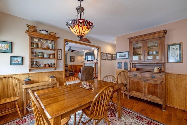 dining area featuring wood finished floors, a wainscoted wall, and ceiling fan