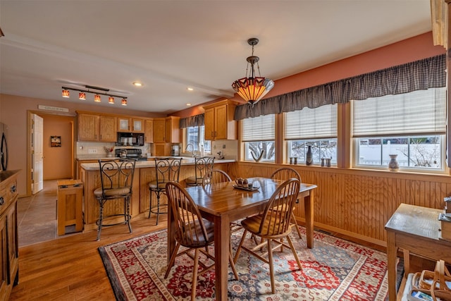 dining room with wooden walls, recessed lighting, and light wood finished floors