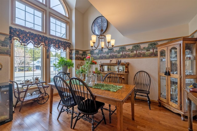 dining room featuring high vaulted ceiling, wood finished floors, wainscoting, and a chandelier