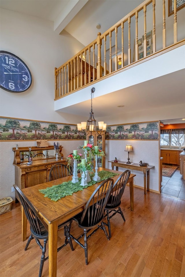 dining space featuring beam ceiling, a notable chandelier, light wood-style floors, and high vaulted ceiling