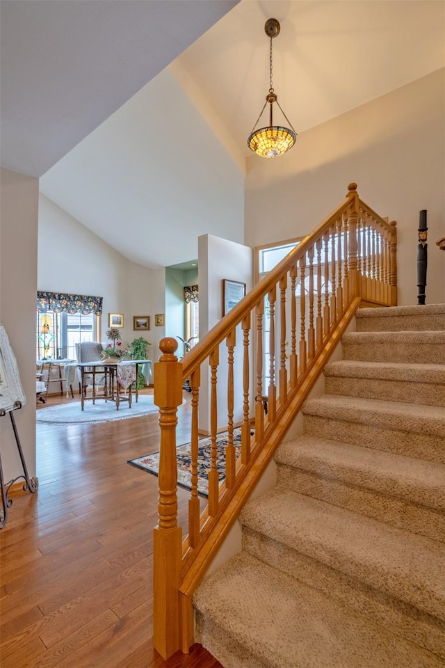 stairway with high vaulted ceiling and wood finished floors