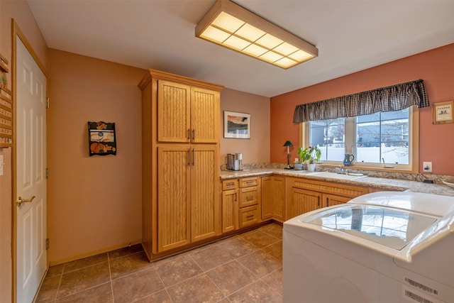 kitchen with a sink, light countertops, and washer and dryer