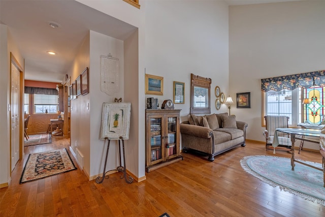 living room featuring visible vents, a high ceiling, baseboards, and light wood-type flooring