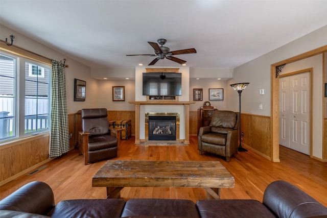 845 S California St, Helena, MT 59601 - living area with wainscoting, wood finished floors, a glass covered fireplace, wooden walls, and a ceiling fan
