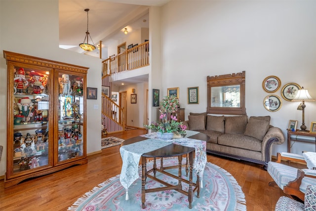 living area with stairway, baseboards, wood finished floors, and a towering ceiling