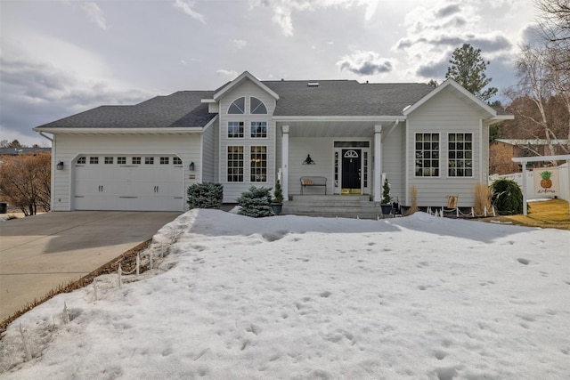 ranch-style home featuring covered porch, an attached garage, a shingled roof, and driveway