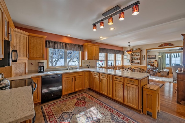 kitchen with a sink, black appliances, a peninsula, and a healthy amount of sunlight