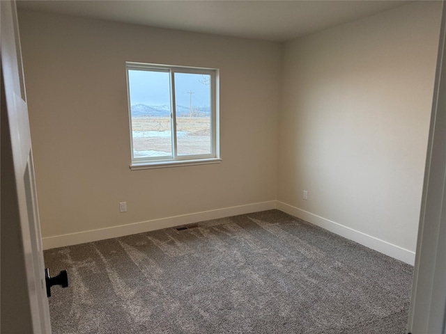 unfurnished room with visible vents, baseboards, and dark carpet