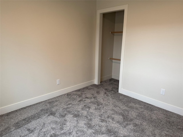 unfurnished bedroom featuring a closet, dark carpet, and baseboards