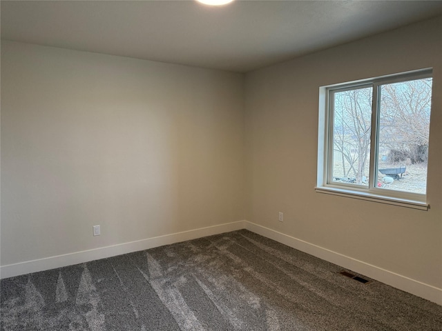 unfurnished room featuring baseboards, visible vents, and dark carpet