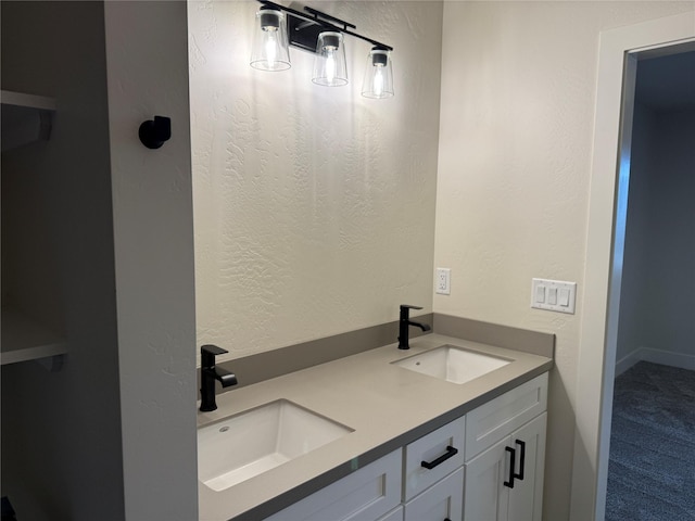 bathroom featuring double vanity, a textured wall, and a sink