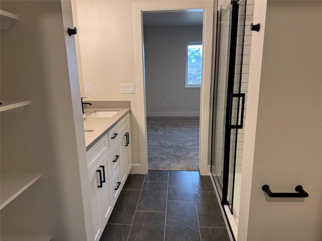 bathroom featuring baseboards, double vanity, a stall shower, tile patterned floors, and a sink