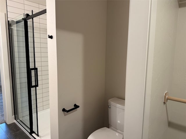 bathroom featuring tile patterned floors, toilet, and a stall shower