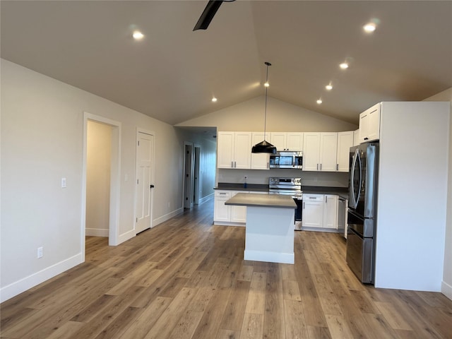 kitchen featuring light wood finished floors, a kitchen island, lofted ceiling, stainless steel appliances, and white cabinetry