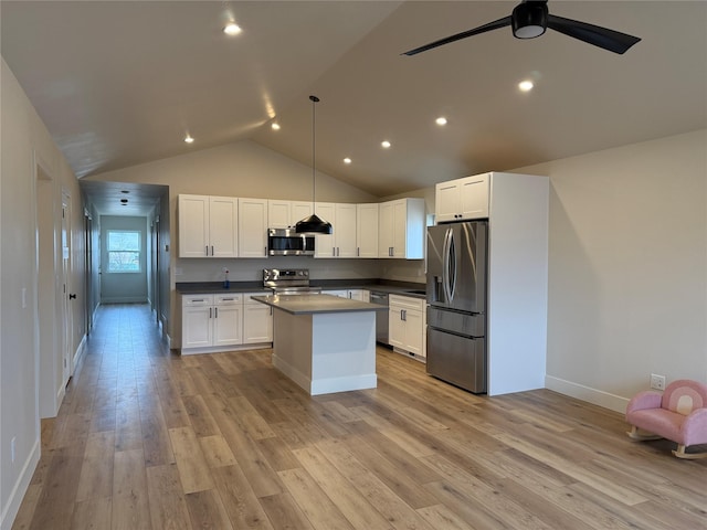 kitchen with a kitchen island, lofted ceiling, light wood-style flooring, appliances with stainless steel finishes, and white cabinetry