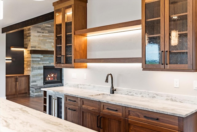 kitchen with wine cooler, light stone countertops, a tile fireplace, and a sink