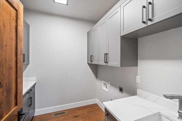 laundry area featuring visible vents, dark wood-type flooring, washer hookup, cabinet space, and hookup for an electric dryer