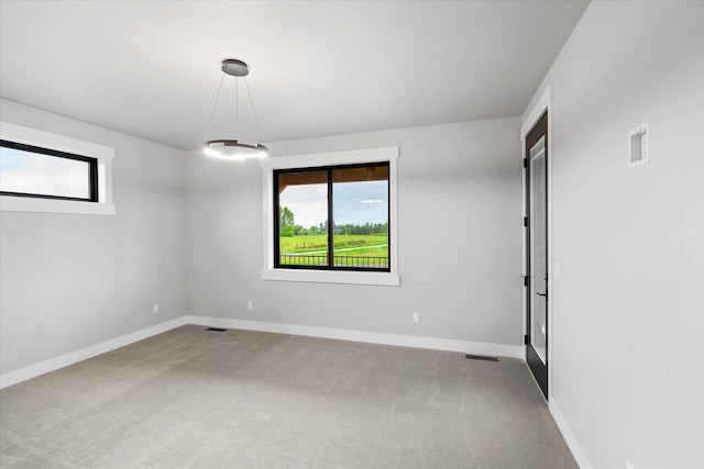 spare room featuring a wealth of natural light, carpet flooring, visible vents, and baseboards