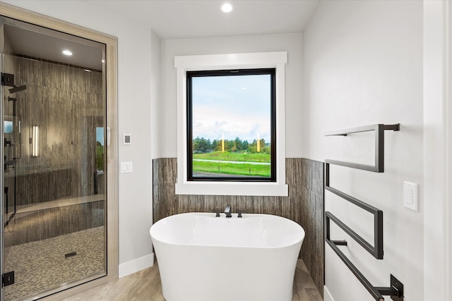 full bath with tile walls, a stall shower, and a freestanding bath