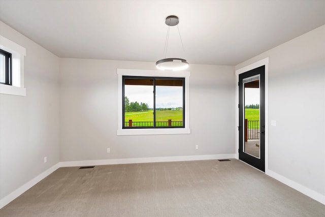 carpeted empty room featuring plenty of natural light, visible vents, and baseboards