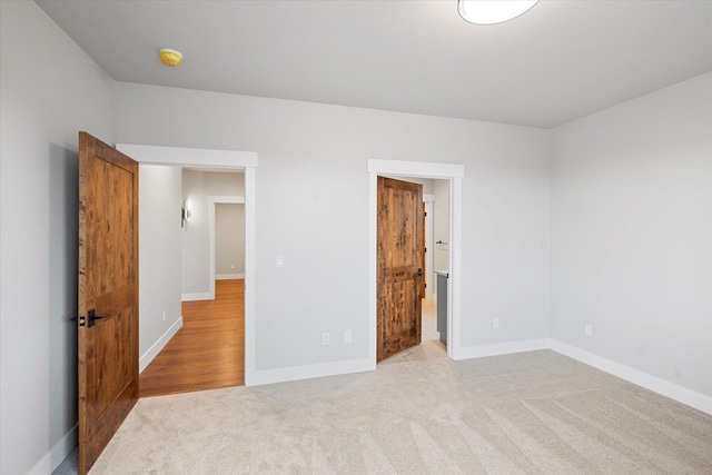 unfurnished bedroom with connected bathroom, baseboards, and carpet flooring