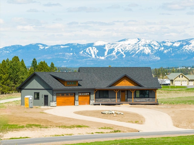 view of front of property featuring a mountain view, stone siding, board and batten siding, and driveway