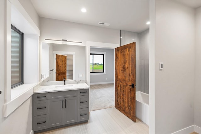 full bathroom with a bath, visible vents, vanity, and baseboards