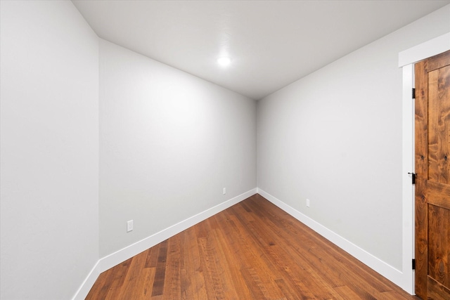 spare room with baseboards and dark wood finished floors