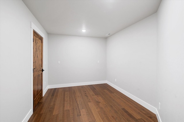 spare room featuring dark wood-type flooring, visible vents, and baseboards