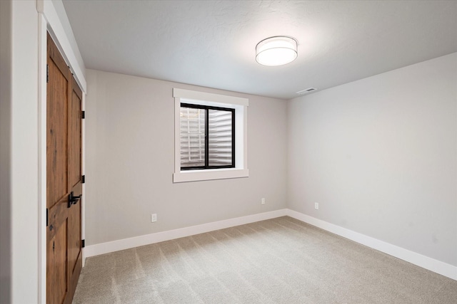 empty room featuring visible vents, baseboards, and light colored carpet