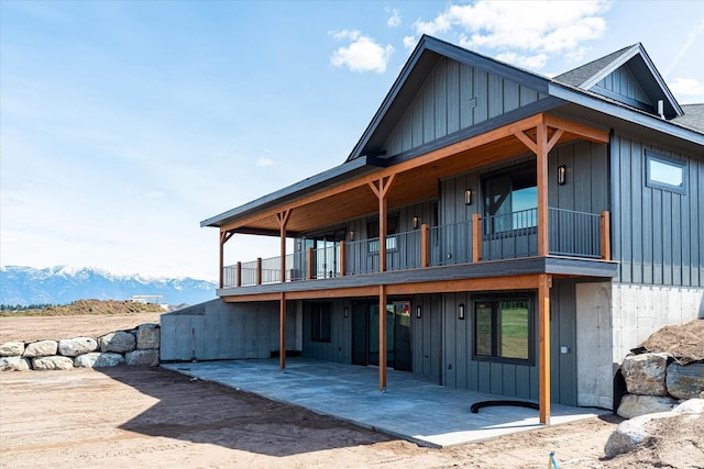 back of property featuring a mountain view, board and batten siding, and a patio