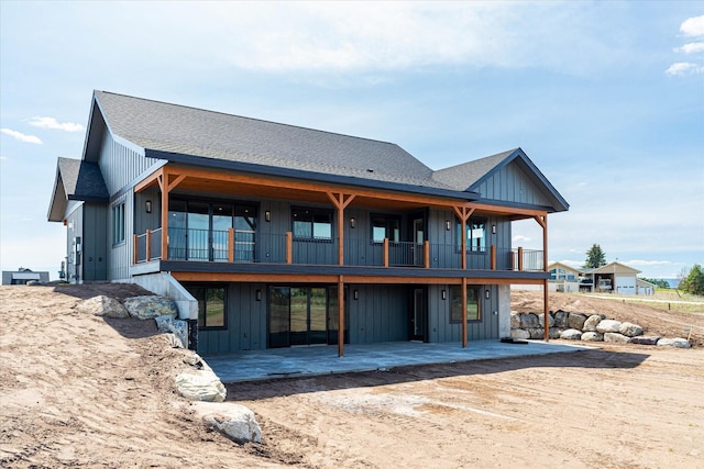 rear view of property featuring a patio, board and batten siding, and a shingled roof