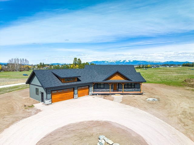 view of front of property with a mountain view, covered porch, dirt driveway, and a shingled roof