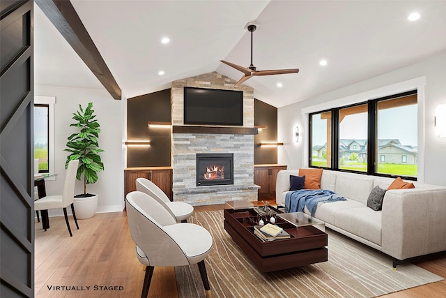 living area with lofted ceiling with beams, a fireplace, light wood-type flooring, and ceiling fan