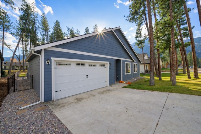 exterior space with concrete driveway, an attached garage, a lawn, and fence